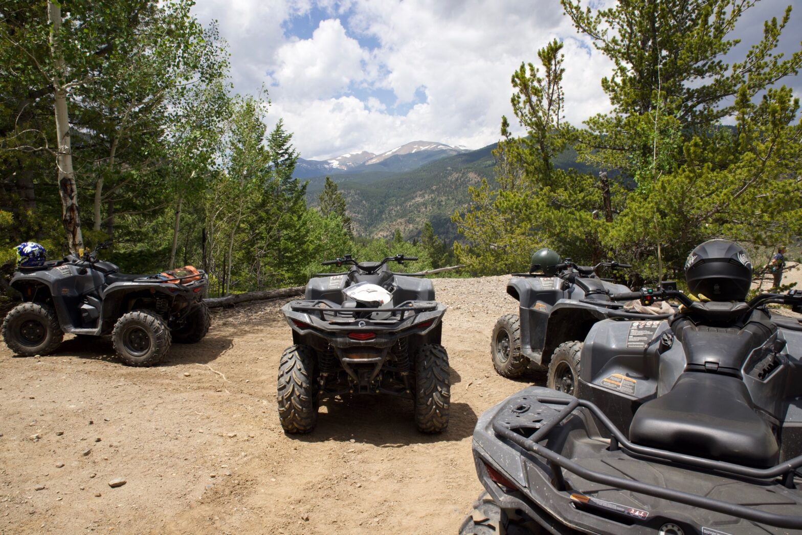 multiple atvs parked on mountain top overviewing the forest