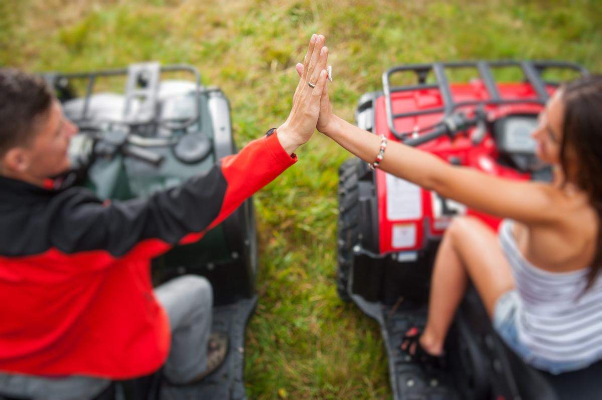 Outdoor Birthday Party Ideas - Two people on ATVs next to each other high fiving